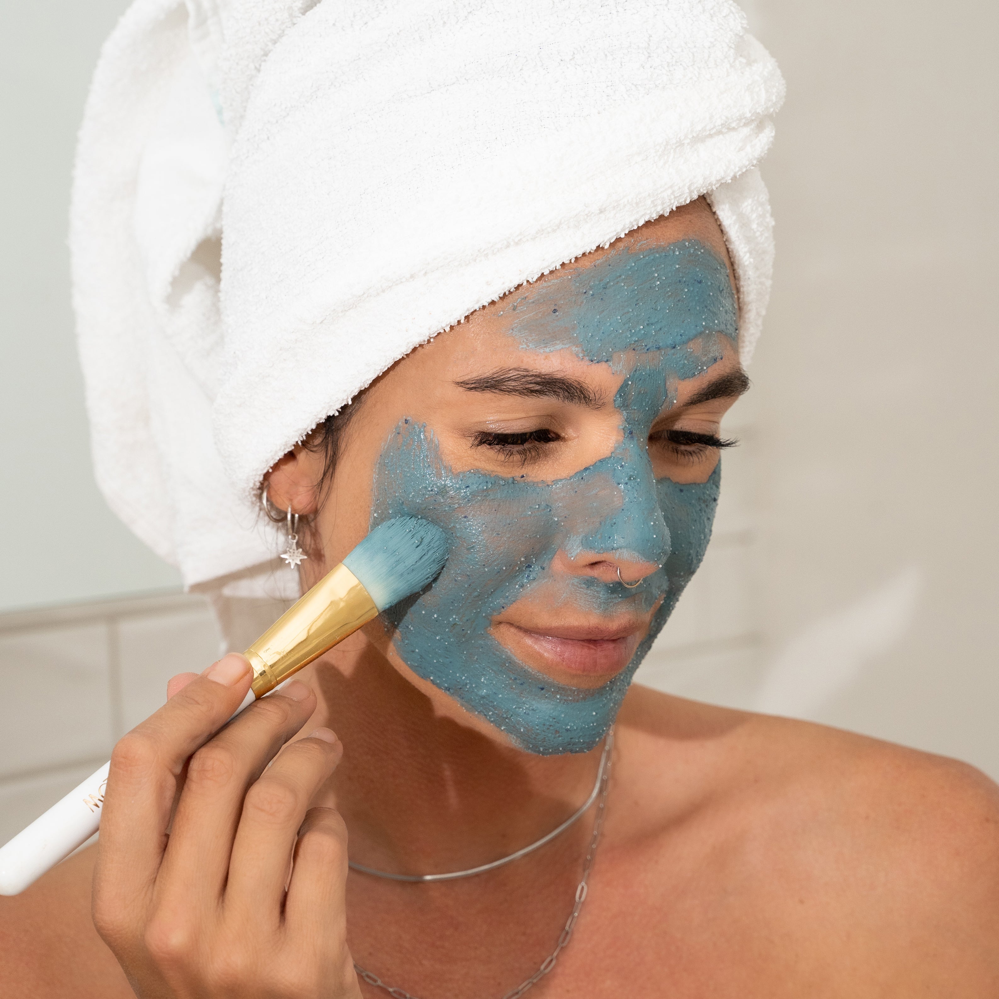 Stray Willow applying blue tansy facial mask to her face with a brush Australian Made